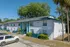 Charming white and teal apartment building surrounded by lush greenery and palm trees, offering a serene living environment.