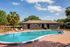 Inviting poolside area featuring a refreshing swimming pool, modern sun loungers, and a cozy clubhouse surrounded by lush greenery in a serene setting.