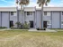 Charming townhouse exterior with modern blue facade and lush palm tree landscaping, perfect for serene living.