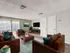 Inviting living room with plush brown leather sofas, vibrant teal cushions, and abundant natural light from large sliding doors.