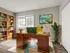 Bright and inviting home office with a wooden desk, vibrant yellow chair, and a well-stocked bookshelf.