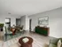 Contemporary dining area with stylish green chairs, a sleek wooden table, and modern art, seamlessly connected to a chic kitchen with black tile accents.