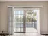 Bright and airy room with sliding glass doors opening to a charming balcony overlooking lush palm trees.