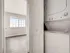 Bright apartment with modern in-unit stacked washer and dryer adjacent to spacious sunlit bedroom featuring large window views.
