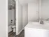 Modern and bright bathroom featuring sleek fixtures, a pristine bathtub, and elegant wood flooring.