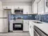 Modern kitchen with sleek stainless steel appliances, elegant white cabinetry, and striking blue subway tile backsplash.