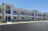 Elegant two-story apartment building with modern design, large windows, and lush landscaping under a clear blue sky.