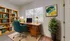 Charming home office with vibrant decor, featuring a stylish desk, teal office chair, large bookshelf with colorful books, and a lush indoor plant for a refreshing work environment.