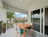 Charming balcony view showcasing a stylish outdoor dining area with a wooden table, surrounded by lush greenery and serene landscape.