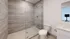 Modern bathroom featuring a sleek glass-enclosed shower, beige tiled walls, and a pristine vanity.