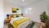 Inviting bedroom featuring a stylish modern design with vibrant decor, plush bedding, and a sunlit window.