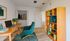 Inviting home office with modern decor, featuring a sleek wooden desk, stylish green chair, and a well-organized bookshelf. Perfect blend of functionality and elegance.