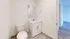 Bright and modern bathroom with sleek fixtures, pristine vanity, and wood-style flooring, ideal for a stylish apartment living.