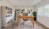 Contemporary home office with a sleek wooden desk, stylish chair, and well-organized bookshelves, illuminated by natural light from a large window.