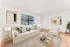 Bright and inviting living room with modern decor, featuring a plush white sofa, elegant artwork, and warm wood flooring.