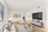 Chic modern living room with natural light, stylish furnishings, and a sleek flat-screen TV.