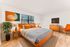 Vibrant bedroom featuring an orange upholstered bed, contemporary furniture, stylish artwork, and a cozy ambiance.