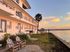 Charming waterfront apartment building with serene sunset views, lush greenery, and cozy outdoor seating.