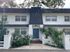 Charming two-story residence with a classic white facade, elegant blue door, and lush greenery.