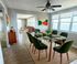 Chic dining area with green velvet chairs and glass table, showcasing modern decor and abundant natural light with stunning ocean views.