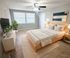 Bright and inviting bedroom with a modern design, featuring a cozy wooden bed, contemporary artwork, and serene natural lighting.