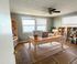 Bright and inviting home office with elegant wooden desk, chic gray chair, and ample shelving space, offering serene water views through large windows.