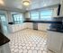 Bright and spacious kitchen with stylish hexagonal tile flooring, sleek black countertops, and ample white cabinetry, complemented by large sunlit windows.