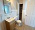 Bright and inviting bathroom featuring modern fixtures, spacious vanity, and convenient open shelving for storage.