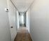 Bright, spacious hallway with modern tile flooring and sleek white walls leading to cozy rooms.