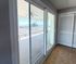Bright interior featuring large sliding glass doors opening to a spacious balcony with stunning ocean views.