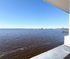 Breathtaking waterfront view from balcony, showcasing expansive blue waters and clear skies, perfect for relaxation.