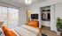 Chic bedroom with vibrant orange accents, featuring a cozy bed, sleek TV, and spacious closet, bathed in natural light.