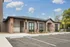 Charming apartment complex entrance with elegant brick accents and well-maintained landscaping under a bright blue sky.
