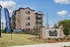 Charming brick apartment complex with modern balconies, welcoming landscaping, and vibrant 'Now Leasing' banners.