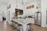 Contemporary kitchen with sleek granite countertops, elegant white cabinetry, and stainless steel appliances, complemented by stylish wooden bar stools and vibrant wall art.