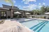 Inviting outdoor space featuring a sparkling pool, shaded seating area with umbrellas, and lush greenery, ideal for relaxation and entertainment.
