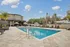 Luxurious outdoor pool area surrounded by elegant lounge chairs and lush palm trees, offering a serene escape with clear blue skies.