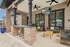 Charming outdoor patio with cozy seating, stylish brick pillars, and a wall-mounted TV, perfect for relaxation and entertaining.