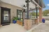 Charming outdoor patio with comfortable seating, rustic brick pillars, vibrant planters, and ceiling fans, ideal for relaxation.