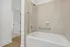 Elegant bathroom with a sleek, modern bathtub, neutral-toned tiles, and convenient safety rails.
