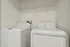 Modern laundry room with sleek white washer and dryer, complemented by practical overhead shelving.