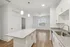 Bright, modern kitchen with sleek granite countertops and elegant white cabinetry, opening into a spacious living area with wood flooring and large windows.