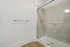 Elegant bathroom featuring a sleek glass shower, modern fixtures, and polished wood flooring, offering a luxurious and serene atmosphere.