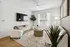 Chic living room with stylish decor, featuring a cozy white couch, elegant area rug, large flat-screen TV, and lush green plant, bathed in natural light.