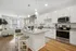 Modern apartment featuring a bright open kitchen with sleek white cabinets and stainless steel appliances, seamlessly flowing into an inviting living area with stylish decor and abundant natural light.