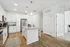 Modern kitchen showcasing sleek white cabinetry, stainless steel appliances, and a stylish central island with pendant lighting.