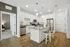 Modern kitchen with stylish white cabinetry, stainless steel appliances, and a cozy breakfast bar in an open-concept apartment.