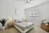 Bright and inviting bedroom with a cozy queen-sized bed, elegant decor, and natural light streaming through large windows.