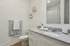 Elegant bathroom featuring sleek granite countertop, modern fixtures, stylish wall decor, and soft lighting.