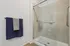 Contemporary bathroom featuring sleek glass shower doors, elegant tiles, and plush navy towels for a luxurious feel.
